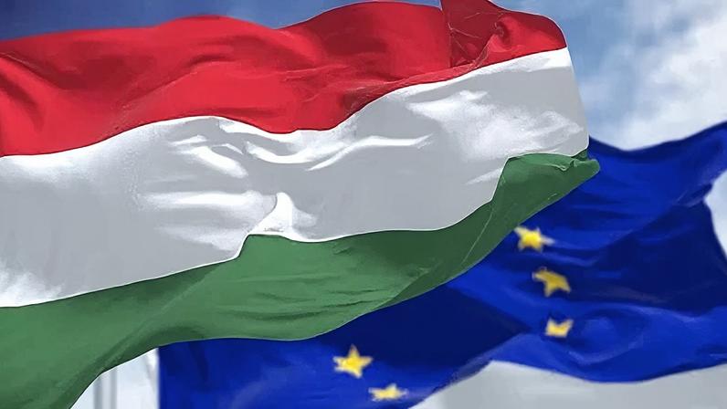 Detalhe da bandeira nacional da Hungria acenando ao vento com bandeira da União Europeia borrada ao fundo