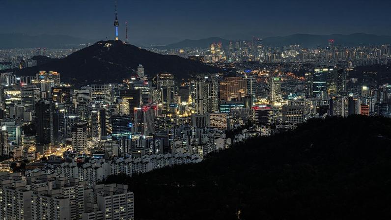 Vista aérea da Torre Namsan de Seul, rodeada pela paisagem urbana de Seul iluminada ao entardecer, a partir da montanha Inwang. Seul, Coreia do Sul (FEBRUARY/Getty Images)
