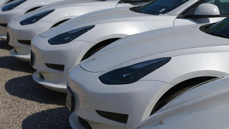 Fileira de carros brancos idênticos estacionados em pátio.