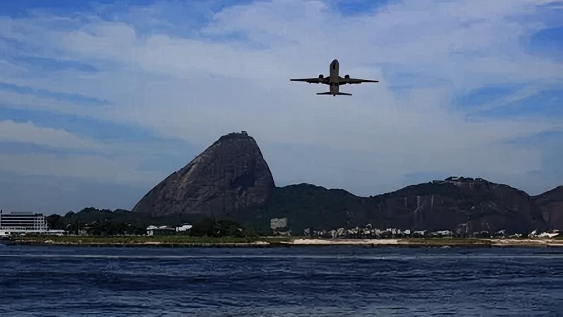 Avião pousando no aeroporto Aeroporto Santos Dumont, no Rio de Janeiro; ao fundo o Pão de Açúcar