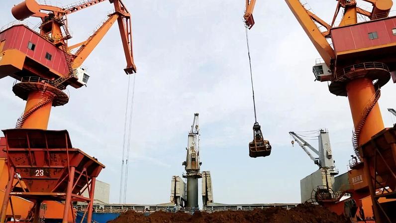 Guindastes descarregam minério de ferro importado de um navio de carga em um porto em Lianyungang, província de Jiangsu, China