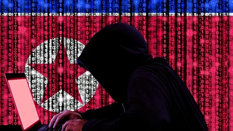 Hacker mexendo em notebook com bandeira da Coreia do Norte no fundo