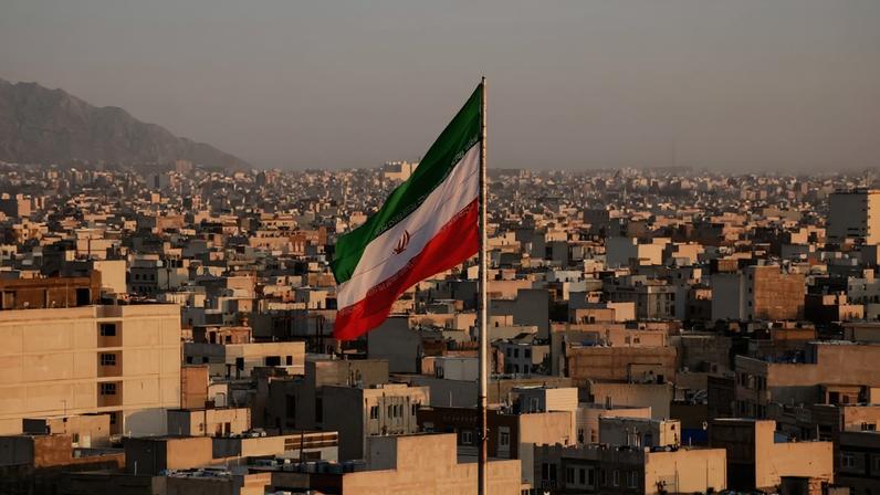 Bandeira iraniana tremulando com paisagem urbana ao fundo em Teerã, Irã