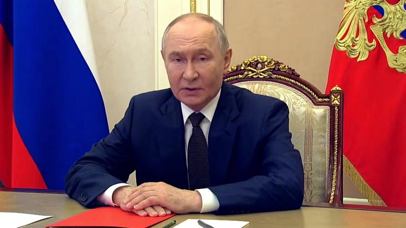 Vladimir Putin sentado com as mãos unidas apoiadas em mesa