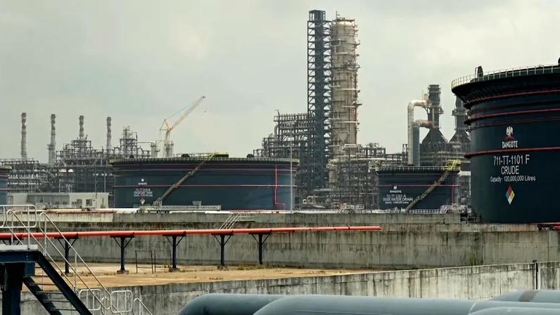 Complexo industrial com tanques e estruturas de refinaria sob céu nublado