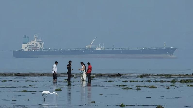 Navio-tanque que transporta petróleo russo ao fundo, no Parque Nacional Marinho de Narara, no Mar Arábico, em Gujarat, Índia.