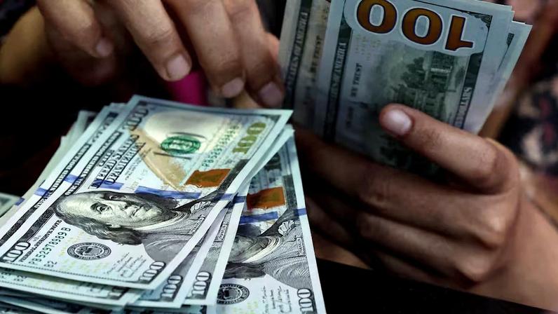 Pessoa conta notas de dólar em uma casa de câmbio em Jacarta, Indonésia