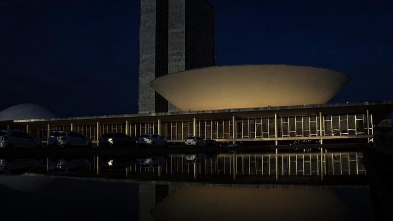 Vista do Congresso Nacional em Brasília, com prédios refletidos em espelho d’água