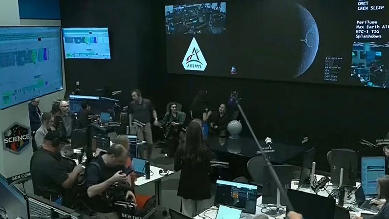 Sala de controle de missão do programa Artemis 2, com técnicos e engenheiros trabalhando em computadores e equipamentos de comunicação