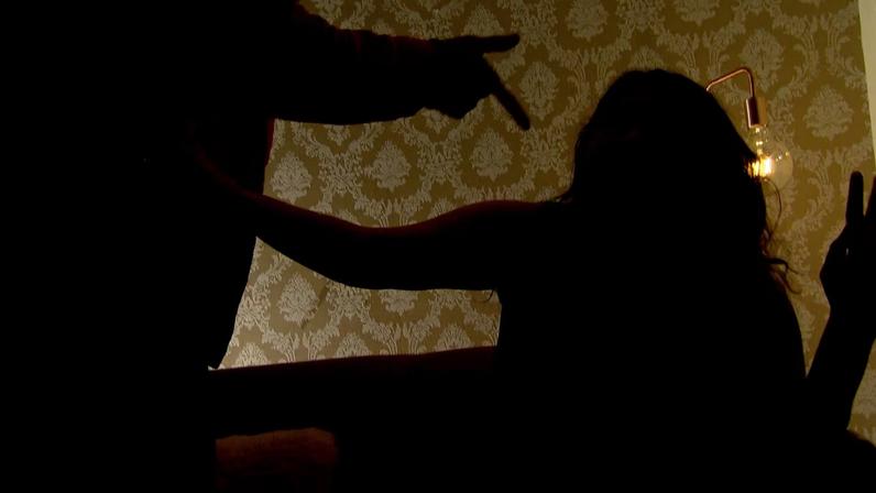 Vemos as silhuetas de um homem que aponta e grita com uma mulher