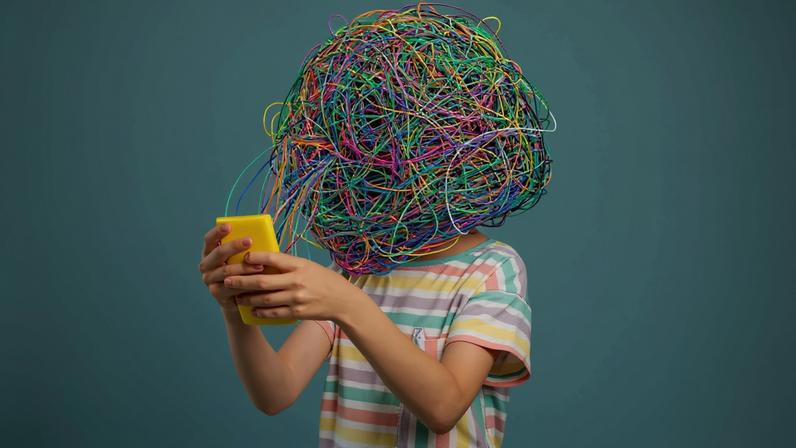 Imagem, em fundo verde, de uma criança com um emaranhado de fios na cabeça usando um smartphone amarelo.