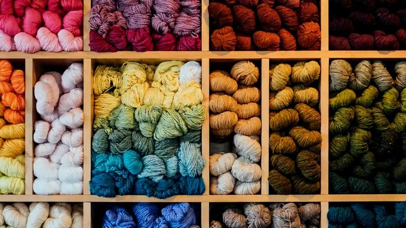 Uma de uma estante com novelos de lã de diversas cores.