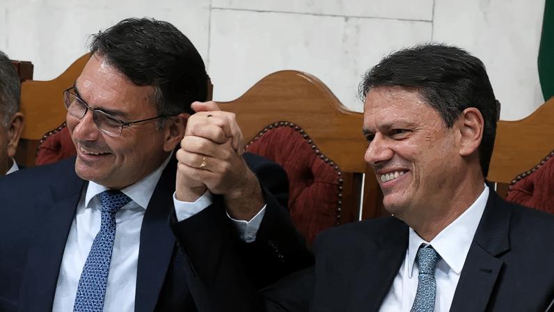 Na imagem, o senador Flávio Bolsonaro (à esq.) e o governador de São Paulo (à dir.) de mãos dadas na Assembleia Legislativa de São Paulo