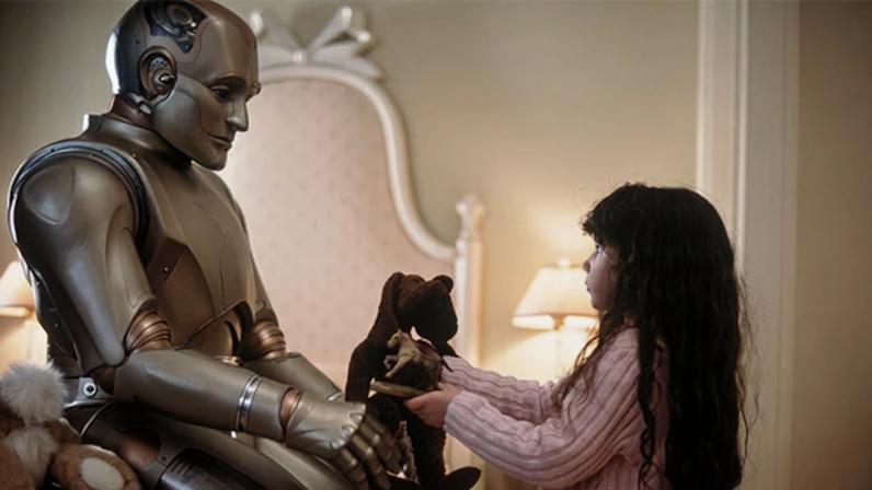 O robô Andrew (Robin Williams) interage com "Little Miss", filha do casal que o comprou, em "O Homem Bicentenário" - Foto: reprodução