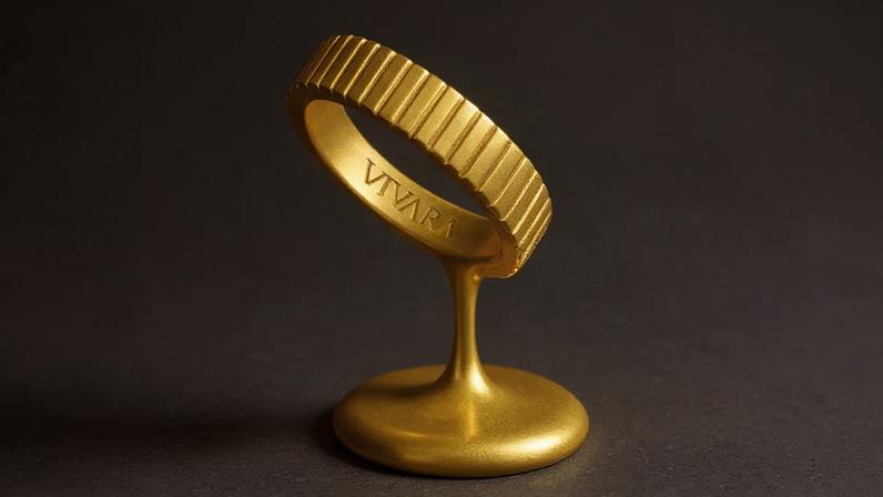 Escultura de anel dourado com ranhuras, "VIVARA" gravado, derretendo em uma base.