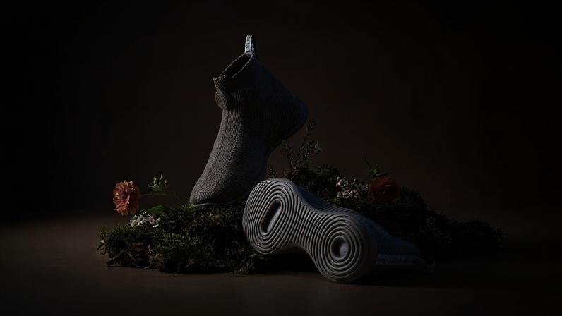 Two sock-like Mo.onshot sneakers arranged on a mossy bed.