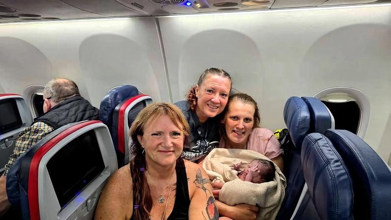 mulheres dentro de avião e neném recém-nascido