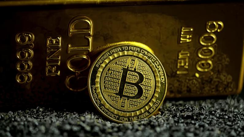 Representação do bitcoin ao lado de barra de ouro