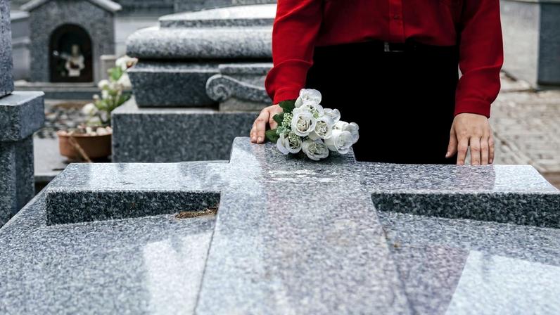 Mulher coloca flores sobre túmulo em cemitério - Metrópoles