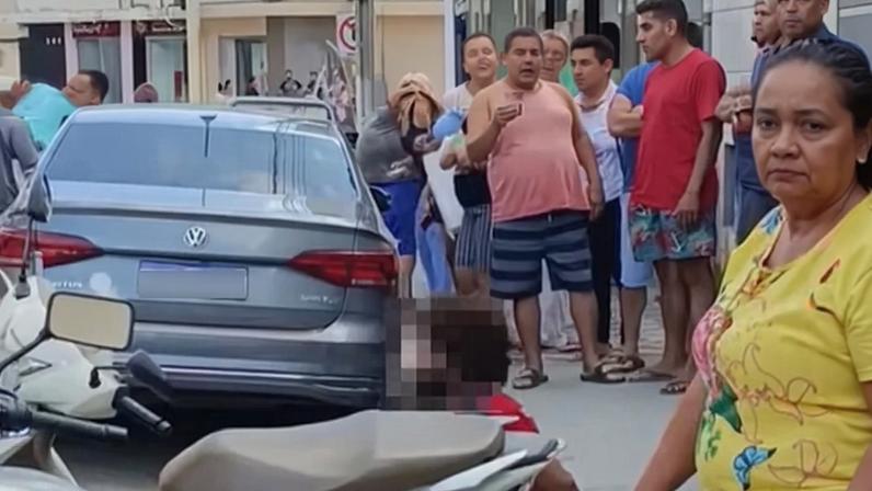 Suspeito (sentado na calçada) foi contido por moradores após esfaquear dono de comércio em Itabirinha