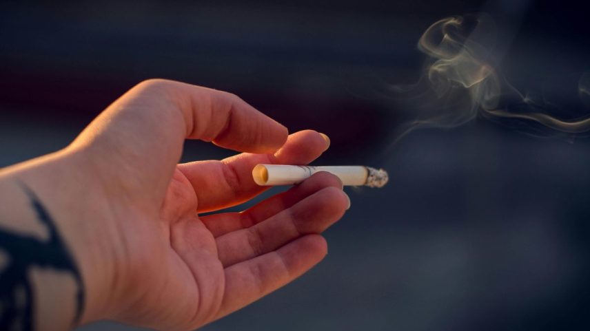 mão segurando um cigarro aceso