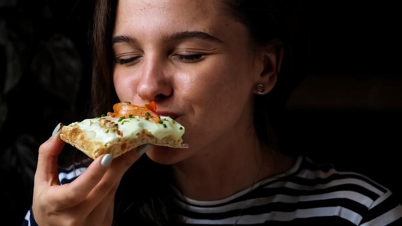 Na foto uma mulher come uma pizza - Metrópoles