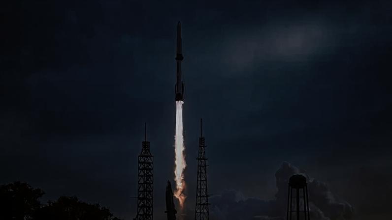 Reuters Blue Origin's New Glenn rocket taking off from a Florida launchpad with a hazy blue sky behind it.