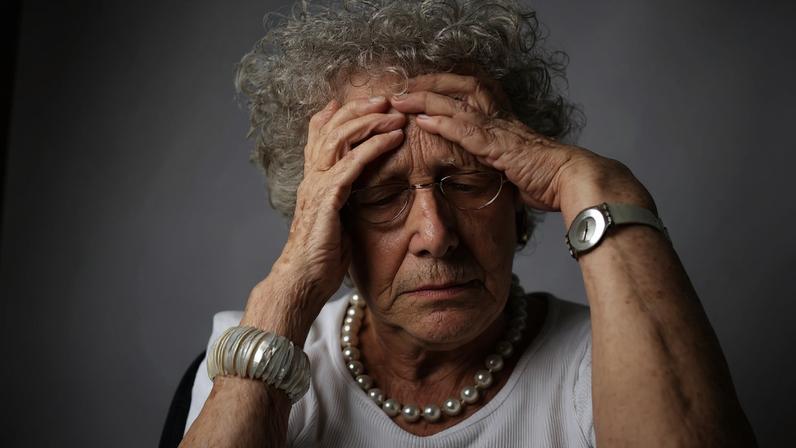 Mulher leva as mãos à cabeça em um sinal de esquecimento, comum em estágios de demência