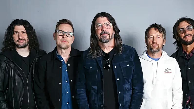 BBC Five members of the Foo Fighters band stand side by side looking directly at the camera, hands in pockets.
