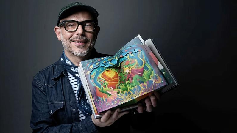 O designer gráfico brasileiro Eduardo Lima, da House of MinaLima, com a recém-lançada edição de 'O Pequeno Príncipe' criada para marcar o 80º aniversário da obra