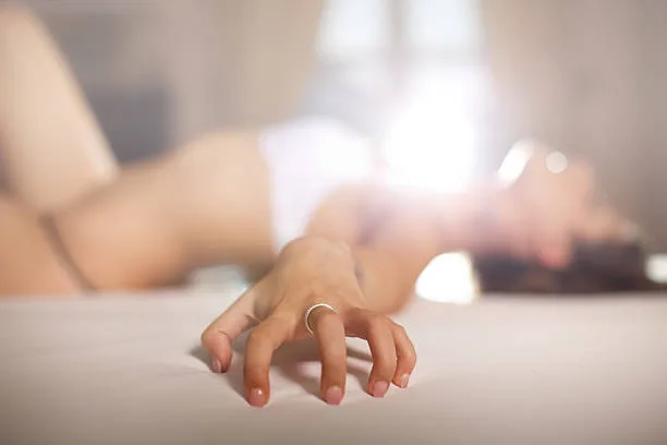 Pretty woman lying in bed and enjoying in passionate pleasure