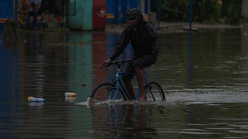 Um homem atravessa uma área alagada de bicicleta após uma forte tempestade que atrasou as eleições em 28 de novembro de 2011 em Kinshasa, República Democrática do Congo.