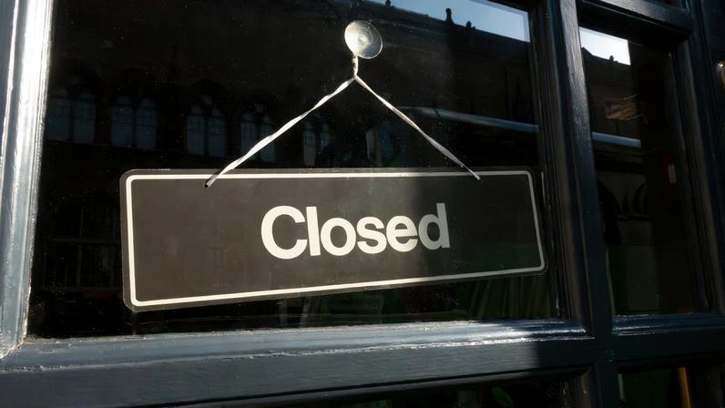 Dark blue entrance to an old small shop with a black closed sign on the glass door