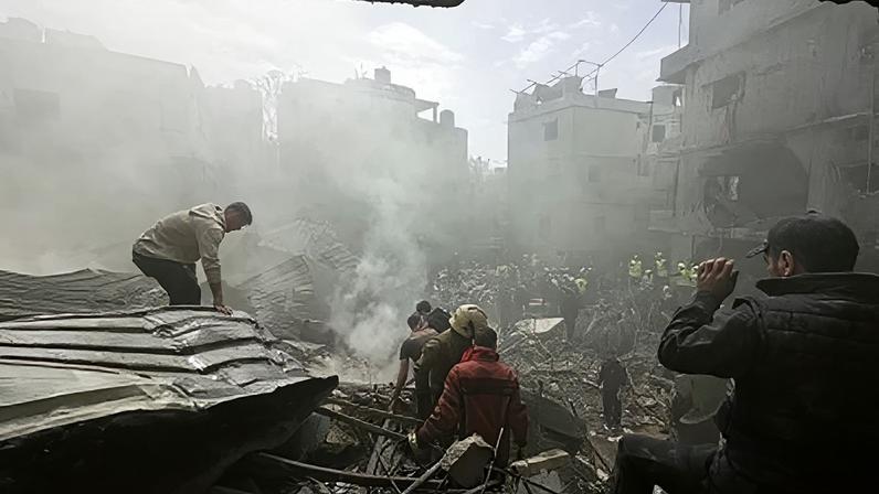 Pessoas se reúnem enquanto equipes de resgate trabalham no local de um ataque israelense na área de Jnah, em Beirute, Líbano, neste domingo