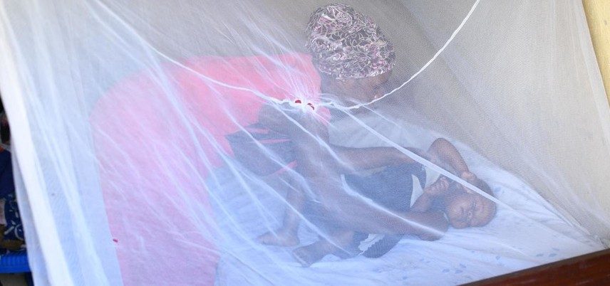 Na zona rural de Uganda, uma mãe coloca seu filho de um ano para dormir dentro de um mosquiteiro