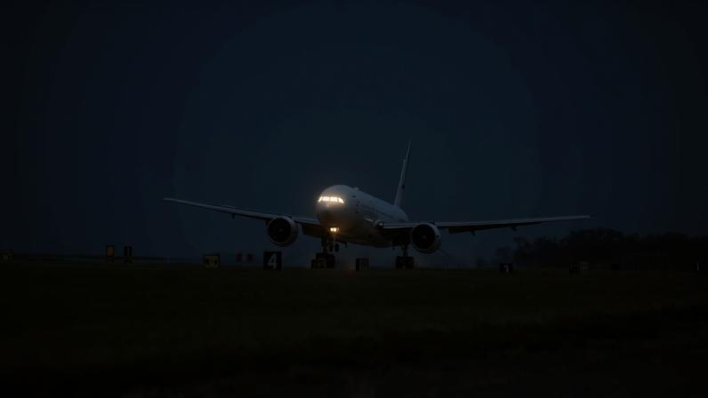 The white 777 aircraft can be seen touching down on a long runway with a row of grass along the pavement at NASA's Langley Research Center.