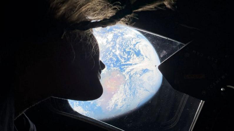 A especialista da missão Artemis II, Christina Koch, olhando para a Terra através da janela da espaçonave Orion - Nasa/Divulgação