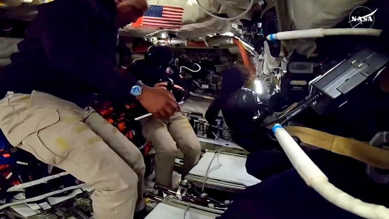 This screengrab from a NASA live broadcast video footage shows NASA astronaut and Artemis II Commander Reid Wiseman (C), NASA astronaut and Artemis II Mission Specialist Christina Koch (R) and NASA astronaut and Artemis II pilot Victor Glover working inside the Orion spacecraft as they pass the halfway point between Earth and the Moon on the way to their planned lunar flyby in the Orion spacecraft, on April 3, 2026. The US space agency's online dashboard showed that the Orion spacecraft carrying the astronauts is now more than 219,000 kilometres (136,080 miles) from Earth. "We're halfway there," NASA posted on social media. (Photo by NASA / AFP)