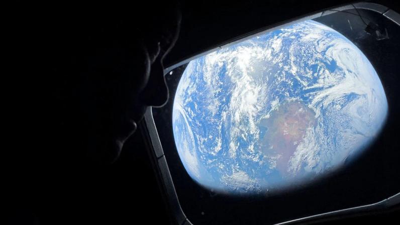 Astronauta Reid Wiseman, da missão Artemis II, observa a Terra pela janela da nave