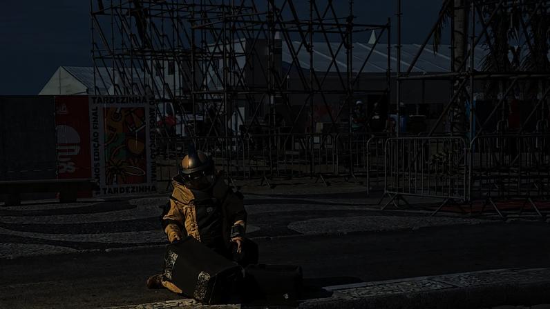 Foto divulgada pela Polícia Civil do Rio de Janeiro mostrando um policial inspecionando uma granada de mão encontrada na praia de Copacabana, no Rio de Janeiro, Brasil, em 13 de abril de 2026