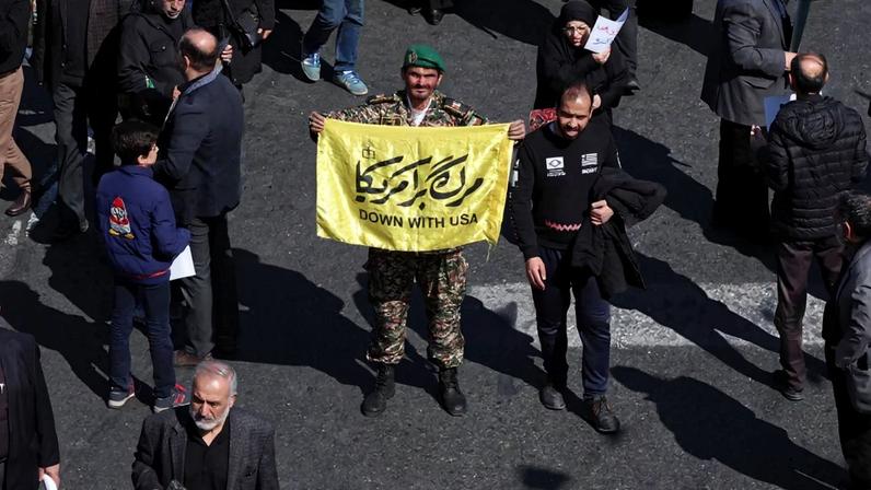 Um militar segura uma faixa enquanto iranianos participam de uma manifestação contra os EUA e Israel