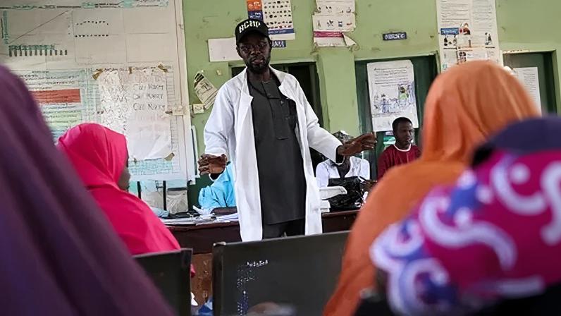 Responsável por centro de atenção primária falando com mães que amamentam em Tudun Gambo, estado de Bauchi, na Nigéria, em 8 de maio de 2025