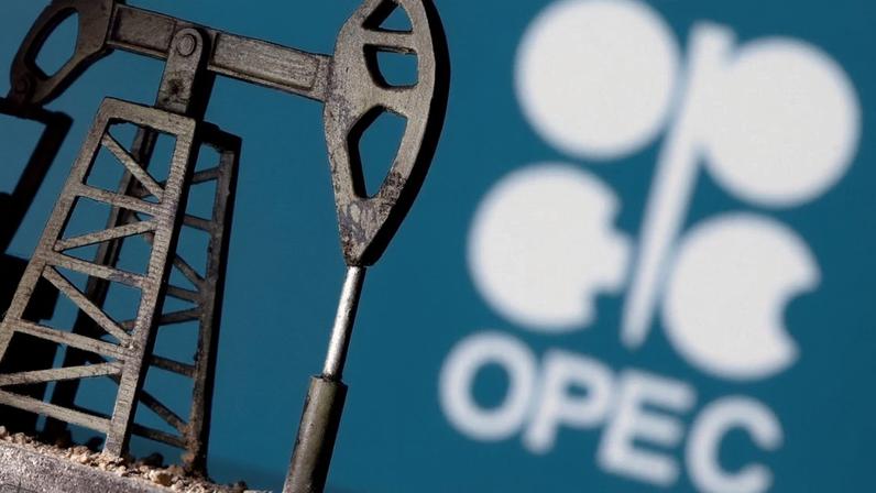 Miniatura de bomba de petróleo com logotipo desfocado da OPEP em fundo azul.