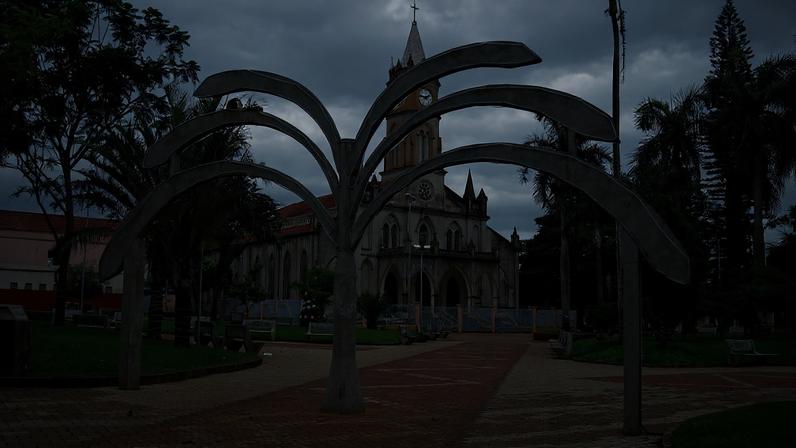 Praça central de Palmital SP, com igreja ao fundo e área arborizada