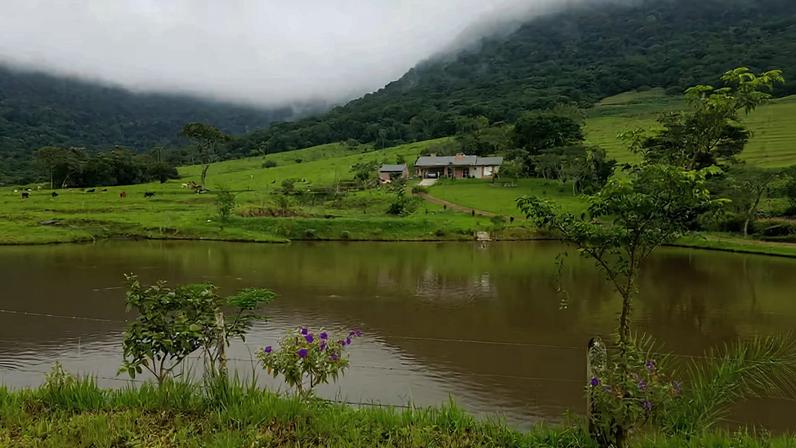 Paisagem da região da Quarta Colônia, área rural com morros, lago e vegetação nativa, sob céu aberto