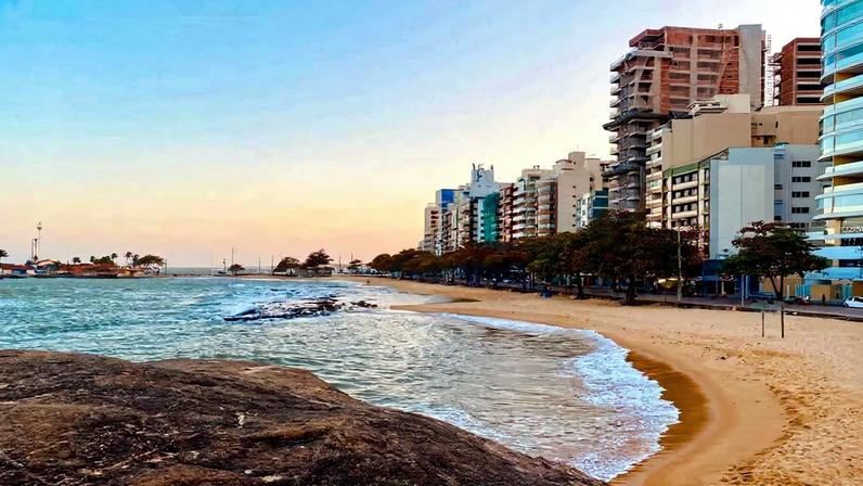 Vista aérea da orla urbana de Guarapari ao entardecer. Crédito: Viajando com a Mala Rosa.