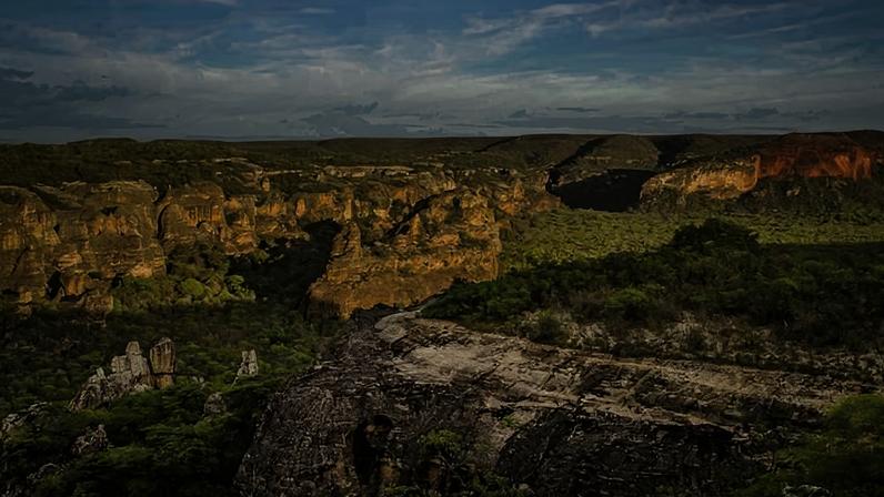 Vista ampla do Parque Nacional da Serra da Capivara no Piauí. Formações rochosas e vegetação de caatinga sob céu claro.