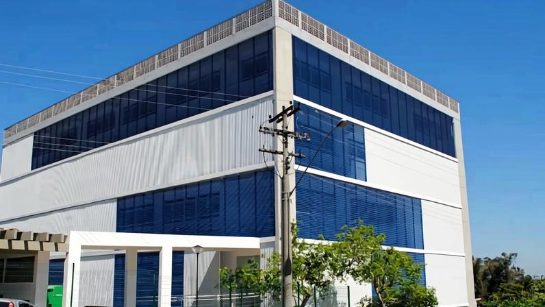 Campus da UNESP em Botucatu, prédio moderno cercado por áreas verdes, em dia claro