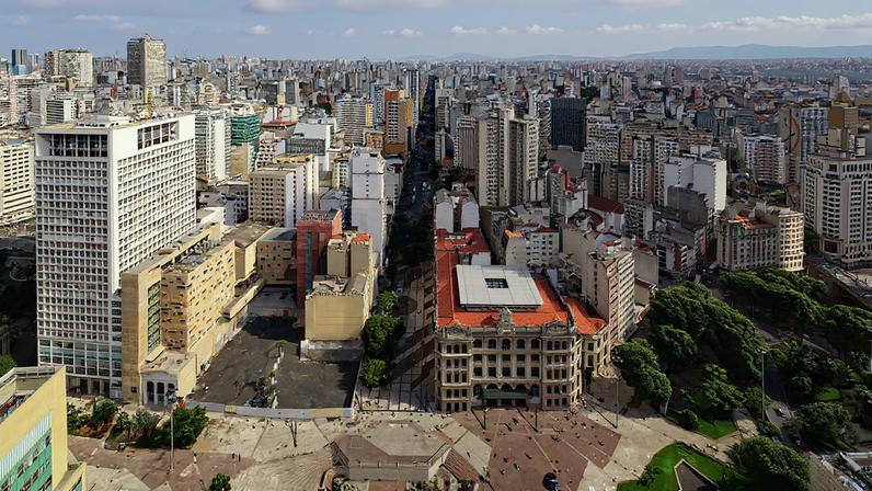 Vista urbana de São Paulo em um dia ensolarado, com prédios e um centro cultural ao fundo