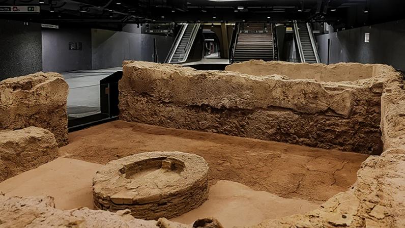 Commuters admire the remains of a Roman bath in the Colosseo-Fori Imperiali Metro C archaeo-station in Rome, with the station steps visible in the background